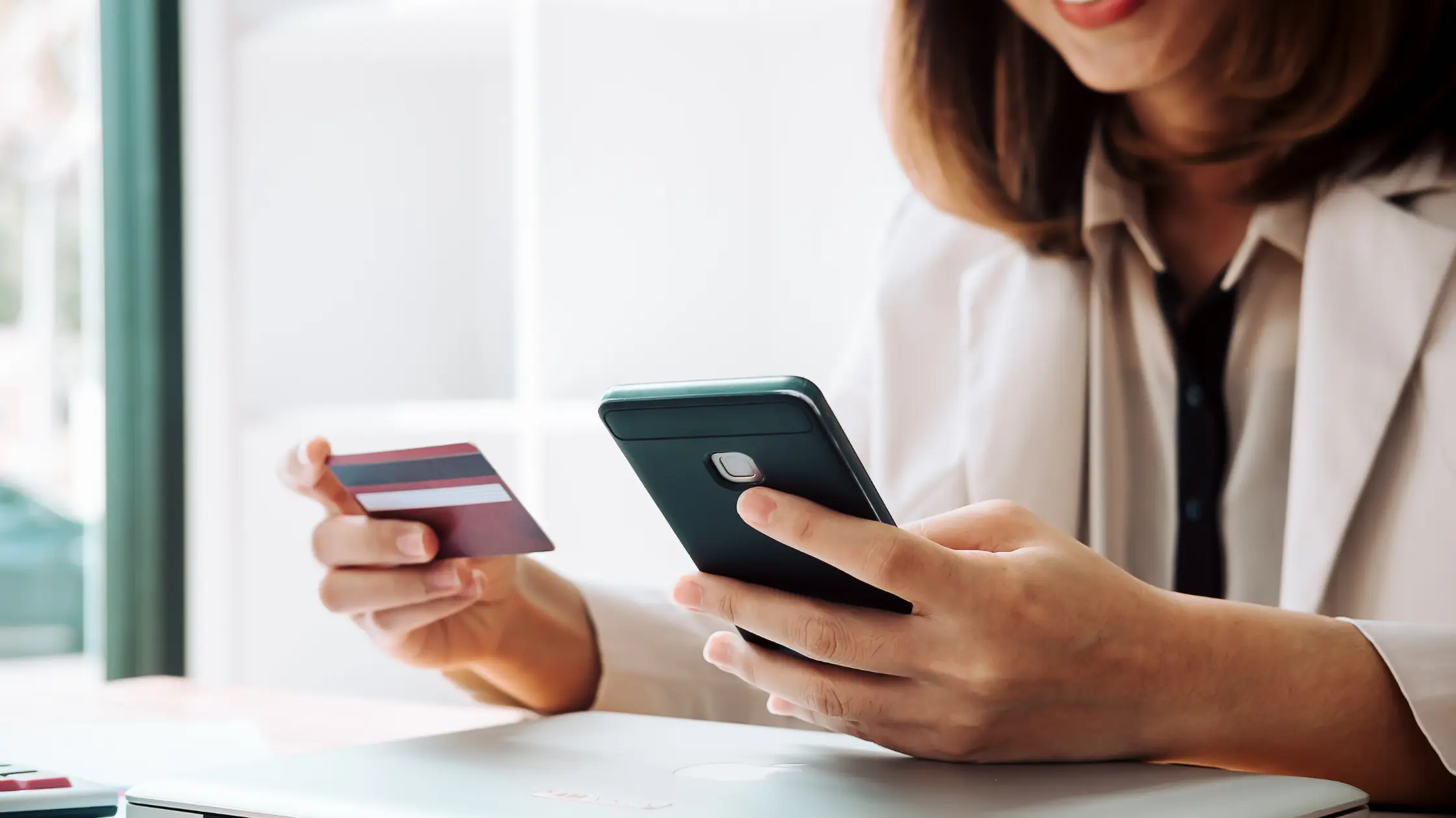 Woman holds credit card and phone for International Payment Processing.